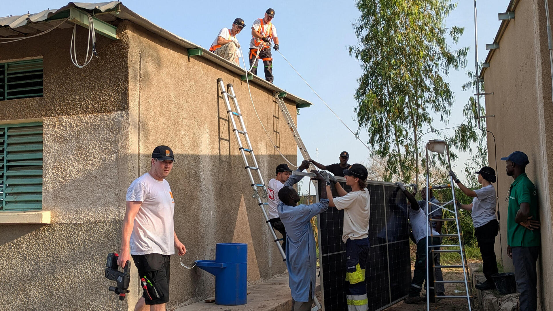 Europäische und afrikanische Auszubildende aus Nürnberg befestigen eine Solaranlage auf dem Dach einer Schule im Senegal.